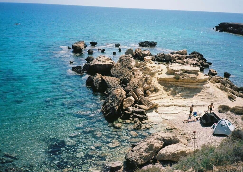 Rocky Cyprus coastline with clear blue sea, ideal for a scenic road trip by rental car
